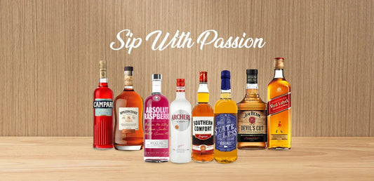 Assorted liquor bottles including whiskey, vodka, and liqueurs on wooden surface with 'Sip With Passion' text