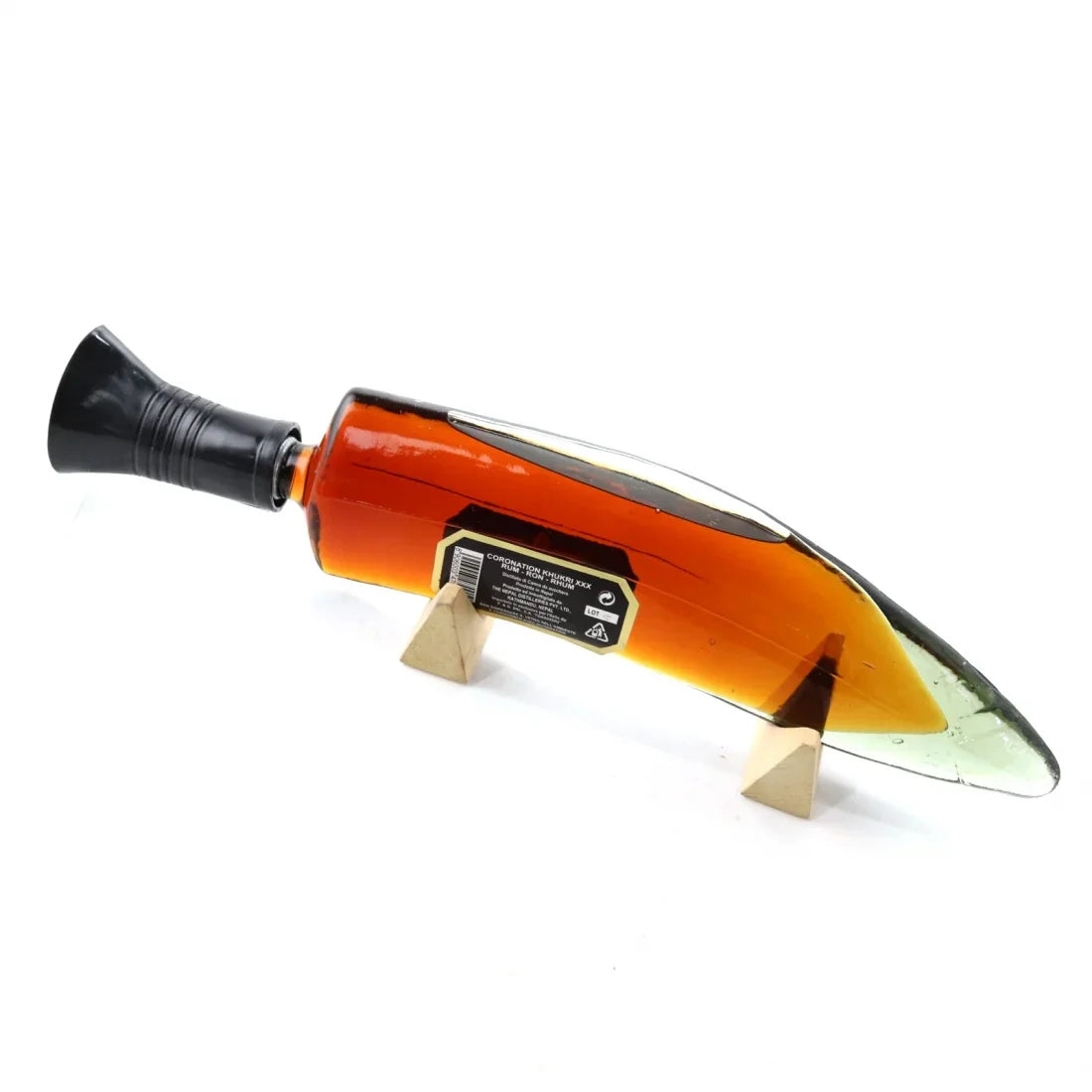 Khukri Coronation Rum bottle shaped like a curved knife on a stand, amber liquid inside