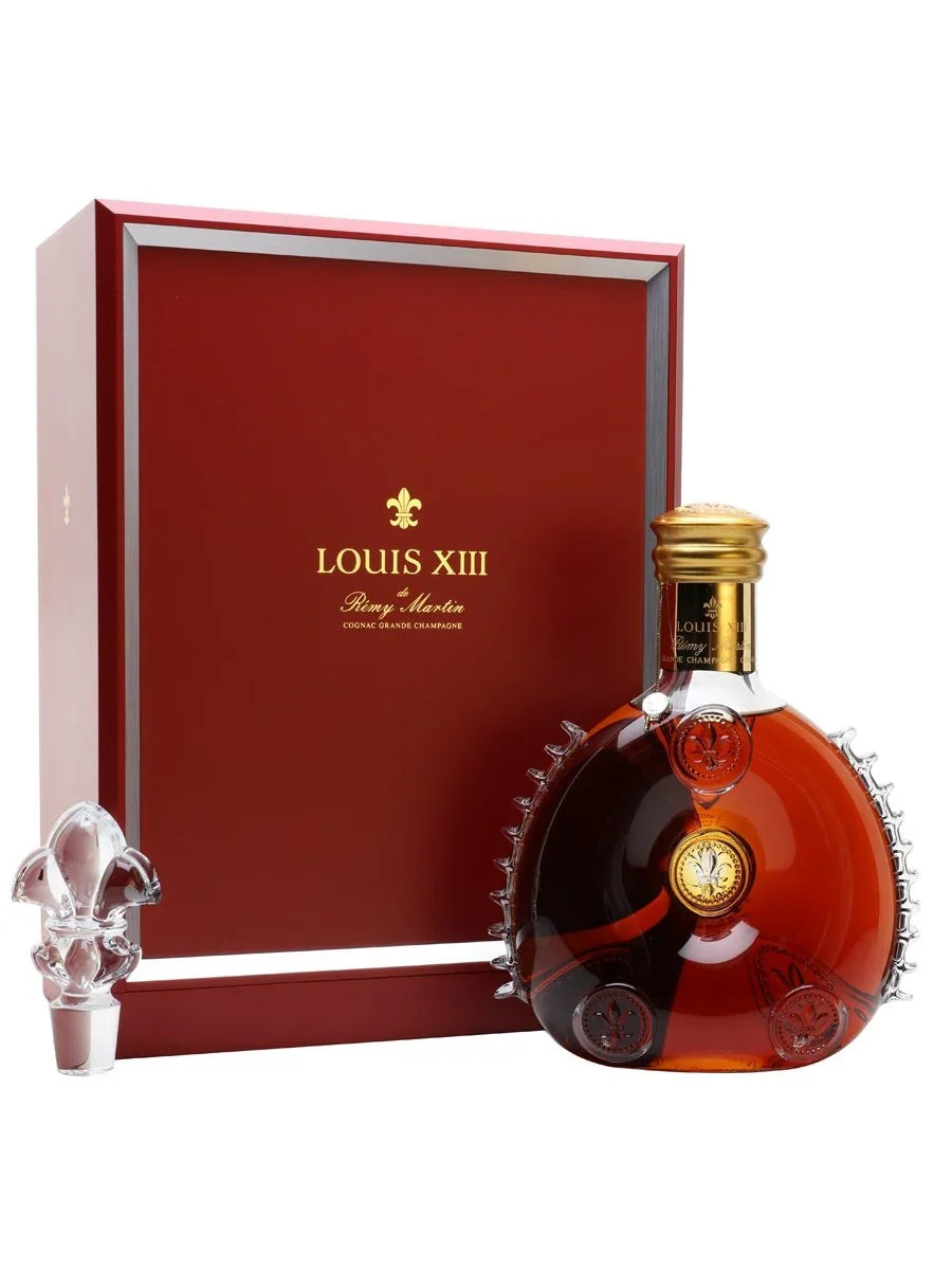Louis XIII cognac bottle with gold cap, fleur-de-lis detailing, red box, and crystal stopper