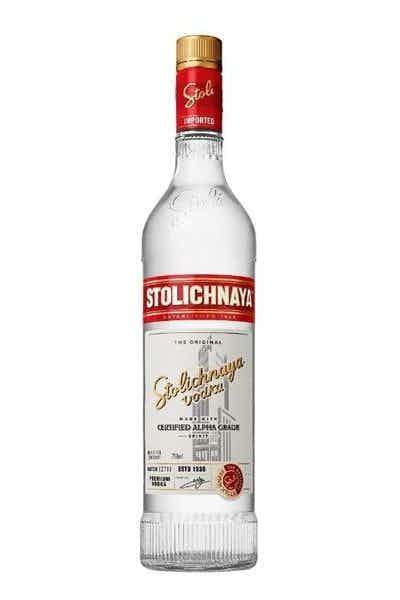 Clear Stolichnaya vodka bottle with red and gold label on a white background